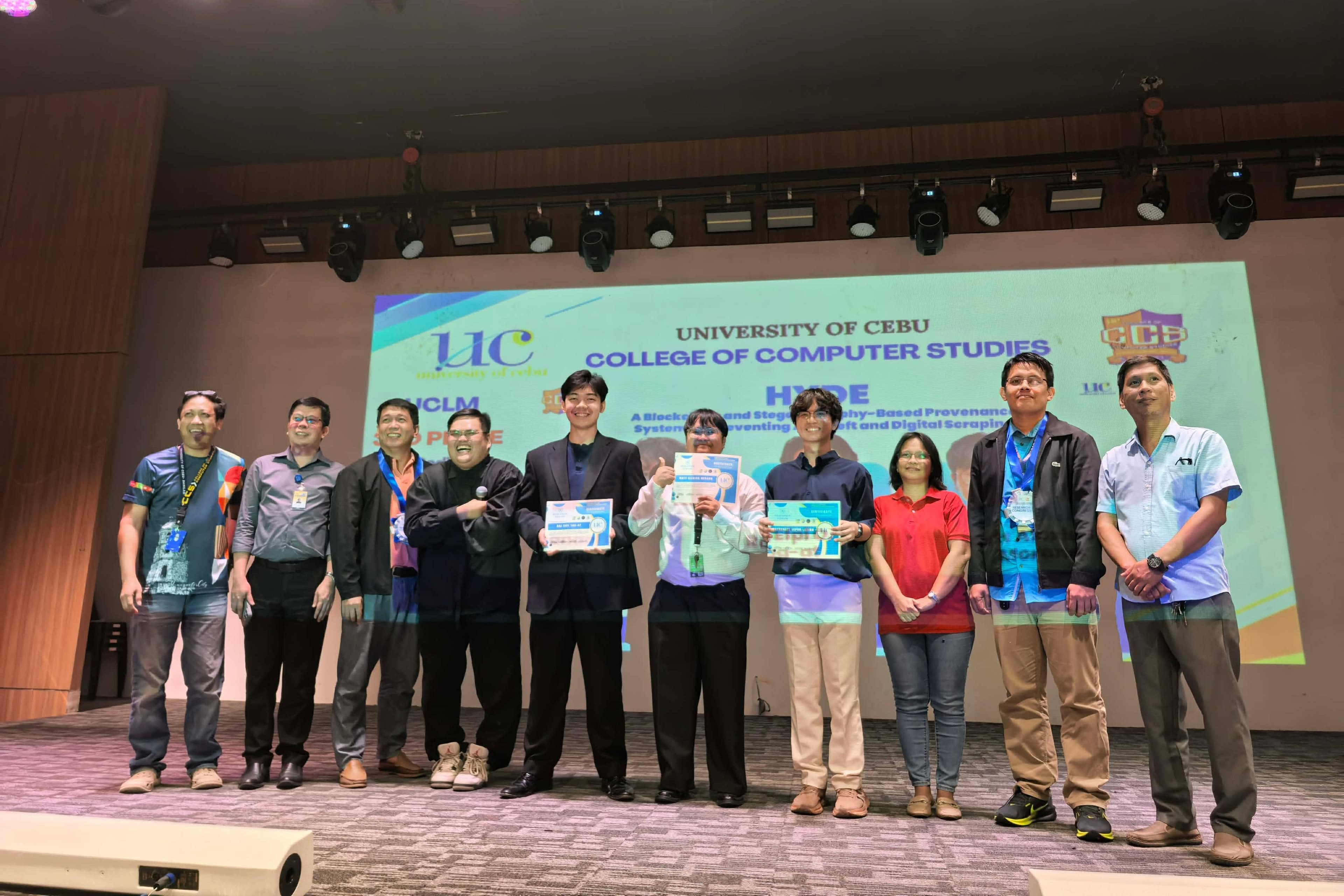 Awardees and faculty posing onstage at the fifth UC College of Computer Studies Research Congress
