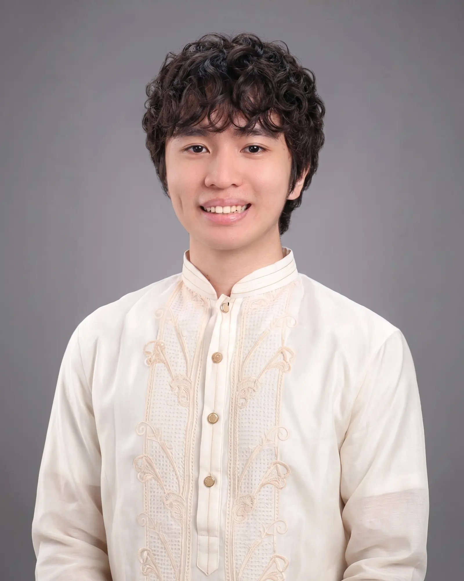 Portrait of Nathanael Larida wearing a cream barong against a gray studio background